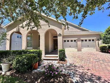 Charming home featuring an arched entryway, two-car garage, and a beautiful brick paver driveway at 15531 Waterleigh Cove Dr, Winter Garden, FL 34787