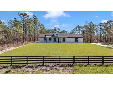 Charming white farmhouse with black trim, wooden columns and a spacious manicured front lawn at 8827 Sw 137Th Ct, Dunnellon, FL 34432