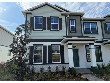 Charming two-story townhome with a combination of white stone and muted green siding, accented by black shutters at 576 Pothos St, Apopka, FL 32703