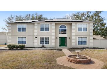 Two-story home featuring a green door, trimmed windows, solar panels, and front yard landscaping at 800 Daybreak Dr, Fruitland Park, FL 34731