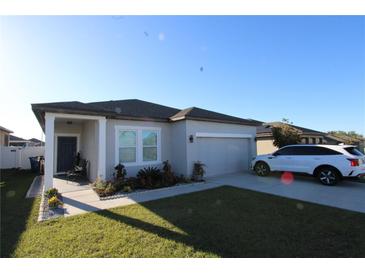Charming single-Gathering home with well-maintained lawn, covered entry, and attached two-car garage at 881 Orchid Grove Blvd, Davenport, FL 33837