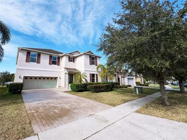 Charming two-story home with landscaped front yard, brick-paved driveway, and attached two car garage at 1208 Sawgrass Pointe Dr, Orlando, FL 32824
