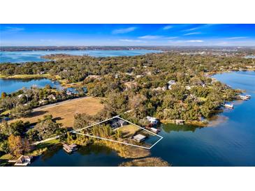 Breathtaking aerial view of lakefront property with lush landscaping, a private dock, and a serene waterfront setting at 647 Ridgewood Dr, Windermere, FL 34786