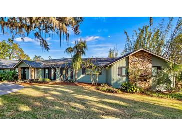 Green house with stone accents, spacious lawn, and mature trees at 647 Ridgewood Dr, Windermere, FL 34786