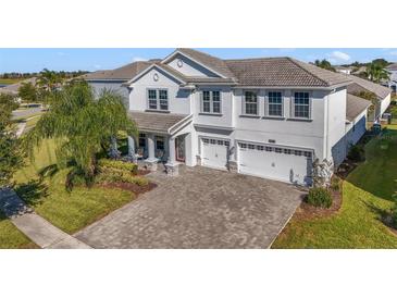 Two-story house with gray exterior, three-car garage, and a paved driveway at 1402 Olympic Club Blvd, Champions Gate, FL 33896