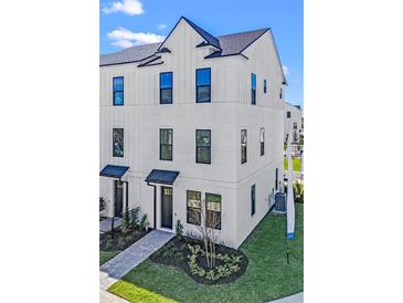 Beautiful three-story townhome with modern design, sleek black windows, and charming walkway leading to the front door at 15142 Grove Lake Dr, Winter Garden, FL 34787