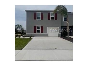 Charming two-story home featuring a well-kept lawn, gray exterior, red shutters, and a concrete driveway at 2729 Golden Trout Ln, Edgewater, FL 32141