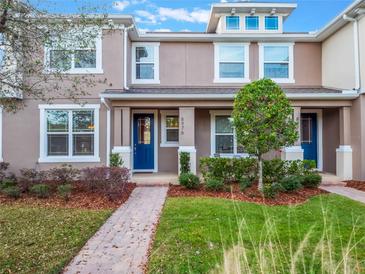 Two-story townhome with a covered porch, landscaped yard, and brick walkway at 8976 Hildreth Ave, Orlando, FL 32832