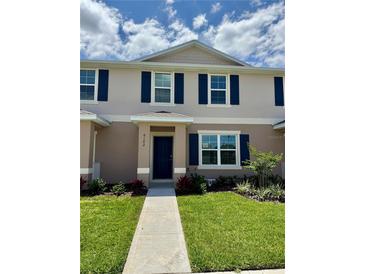Charming two-story townhome featuring blue shutters, a well-manicured lawn, and a welcoming walkway to the front door at 6102 Galloping Dr, Apopka, FL 32712