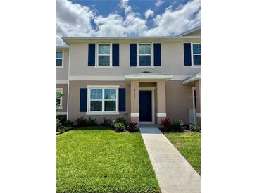Charming two-story home boasts a well-manicured lawn, a blue door, and elegant blue shutters at 6106 Galloping Dr, Apopka, FL 32712