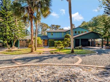 Unique teal home with circular driveway, landscaping, and palm trees at 6320 Rocky Point Rd, Lake Wales, FL 33898