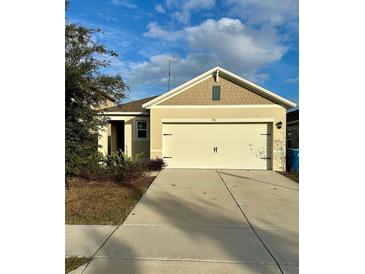 Charming single-story home featuring a tan stucco exterior, two-car garage, and well-maintained landscaping at 791 Chinoy Rd, Davenport, FL 33837