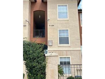 Apartment complex exterior featuring neutral tones and gated entrance with green foliage at 5542 Metrowest Blvd # 206, Orlando, FL 32811