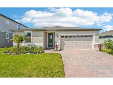 Charming single-story home with a well-manicured lawn, inviting brick driveway, and a two-car garage at 1124 Griffon Ave, Lake Alfred, FL 33850