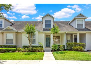 Charming townhome featuring well-maintained landscaping and a welcoming teal front door at 14480 Chinese Elm Dr, Orlando, FL 32828
