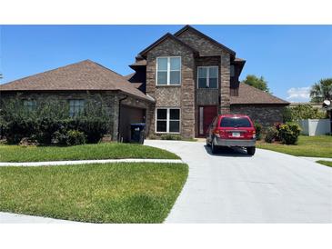 Two-story brick house with a brown roof, attached garage, and a long driveway at 2355 Abalone Blvd, Orlando, FL 32833