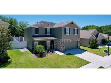Two-story home featuring stone accents, well-manicured lawn, and a two-car garage at 1727 Wood Path, Auburndale, FL 33823