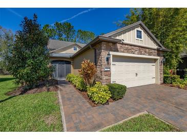 Charming home featuring a manicured lawn, stone accents, and a two-car garage under a clear blue sky at 513 San Sebastian Ct, Davenport, FL 33837