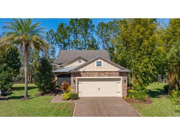 Charming home exterior features a brick driveway, stone accents, lush landscaping, and a two-car garage at 513 San Sebastian Ct, Davenport, FL 33837