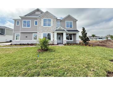 Charming two-story home with stone accents, manicured lawn, and freshly planted landscaping at 977 Hawksnest Pt, Oviedo, FL 32765