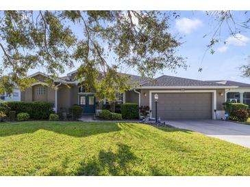 Charming single-story home with a well-manicured lawn, mature trees, and an attached two-car garage at 27601 Country Stone Ct, Leesburg, FL 34748