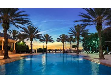 Stunning community pool lined with palm trees, lounge chairs, and a beautiful sunset at 7652 Whisper Way # 104, Reunion, FL 34747