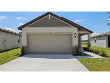 Home featuring an attached garage, concrete driveway, and manicured lawn at 2526 Linda Knoll Ln, Bartow, FL 33830