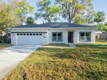 Charming single-story home featuring a large front yard, a two-car garage, and stone accents at 765 W Lansdowne Ave, Orange City, FL 32763
