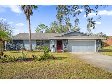Charming single-Gathering home features a well-manicured front lawn with vibrant landscaping, stone accents, and a two-car garage at 1608 Bomi Cir, Winter Park, FL 32792