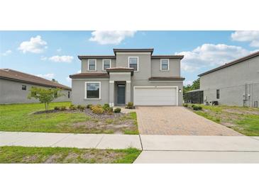 Two-story house with gray siding, a two-car garage, and a landscaped front yard at 220 Macaulays Cv, Haines City, FL 33844