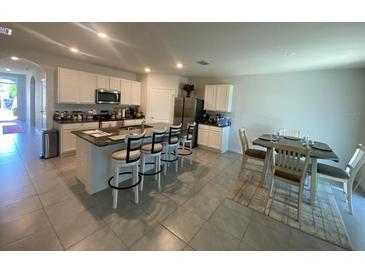 Open-concept kitchen and dining area with island seating and stainless steel appliances at 2723 Sunkissed Dr, St Cloud, FL 34771