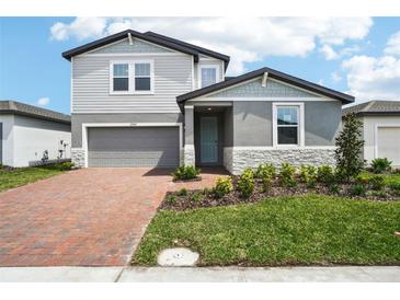 Charming two-story home features a brick driveway, gray siding, and well-maintained landscaping at 2949 Wild Olive Dr, St Cloud, FL 34772