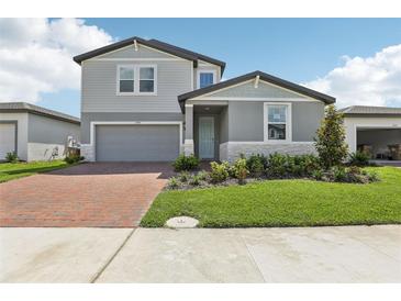Charming two-story home boasts a well-manicured lawn, brick driveway, and attached garage at 2949 Wild Olive Dr, St Cloud, FL 34772