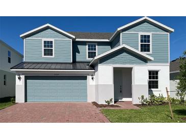 Two-story home featuring blue siding, a brick walkway, a gray garage door, and well-maintained landscaping at 2059 Town Pasture Dr, Eustis, FL 32726