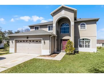 Two-story home boasting an attached garage, well-manicured lawn, and an arched entryway with a large window at 1907 Lakeview Way, Kissimmee, FL 34759