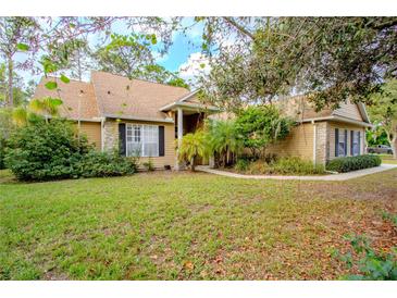 One-story house with tan siding, stone accents, and a landscaped lawn at 6408 Shoreline Ct, St Cloud, FL 34771