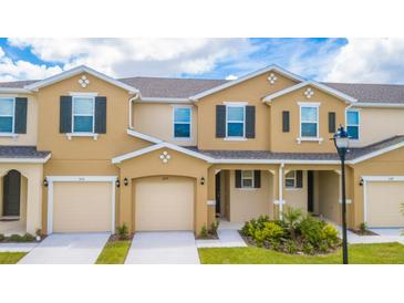 Tan two-story townhome with two-car garage and landscaping at 5149 Adelaide Dr, Kissimmee, FL 34746