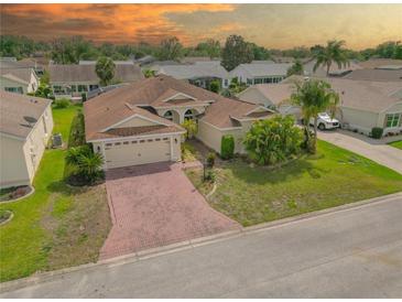 Charming single-story home with a well-manicured lawn, brick driveway, and two-car garage at 4731 Summerbridge Cir, Leesburg, FL 34748