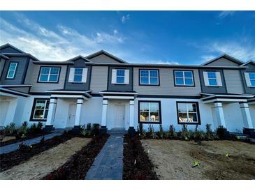 Two-story townhome with gray siding, white accents, and a paved walkway at 600 Pothos St, Apopka, FL 32703