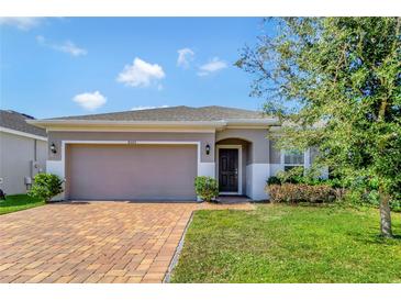 Single-story house with a two-car garage and brick paver driveway at 9355 Westmorely St, Groveland, FL 34736