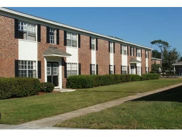 Apartment building showing red brick, black shutters, neatly manicured green lawns, and sidewalks at 5317 Curry Ford Rd # J101, Orlando, FL 32812