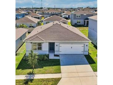 Single-story home with gray exterior, two-car garage, and landscaped lawn at 1656 Aspen Ave, Davenport, FL 33837