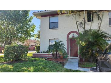 Two-story condo with red door, landscaping, and walkway at 1724 Silver Creek Ct # 105, Orlando, FL 32807