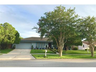 Charming single story home featuring a manicured lawn, lush landscaping, and an attached garage at 5138 Andrea Blvd, Orlando, FL 32807