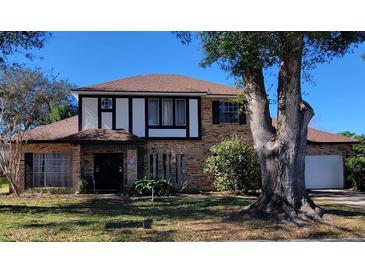 Charming two-story brick home with dark trim, a manicured lawn, and a large tree in the front yard at 9130 Dollanger Ct, Orlando, FL 32819