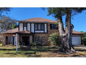 Brick, two-story house with mature landscaping and a large tree in the front yard at 9130 Dollanger Ct, Orlando, FL 32819