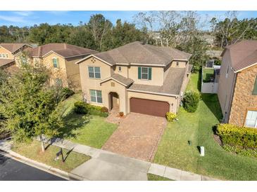 Two-story house with a brown roof, brick driveway, and well-manicured lawn at 1918 Arden Oaks Dr, Ocoee, FL 34761