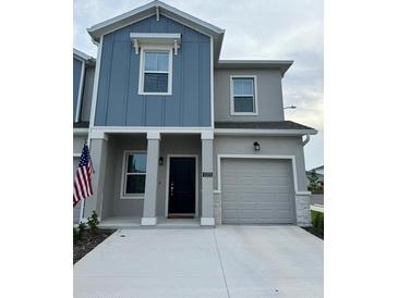 Two-story house with gray and blue siding, two-car garage, and American flag at 3203 Laurent Loop, Davenport, FL 33837