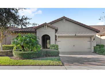 Single-story home with a tile roof, neutral color scheme, and a two-car garage at 10713 Berry Creek Rd, Orlando, FL 32836