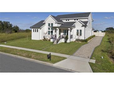 A well-manicured lawn leads to this two-story modern home with black accents, stone walkway, and a driveway at 3705 Ridge Run Dr, Minneola, FL 34715